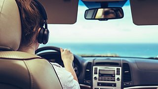 Mag je een koptelefoon of oordopjes dragen tijdens het autorijden? En hoe zit dat in het buitenland?